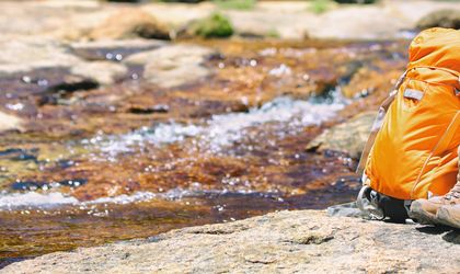 Campingrucksack und Schuhe stehen am Fluß