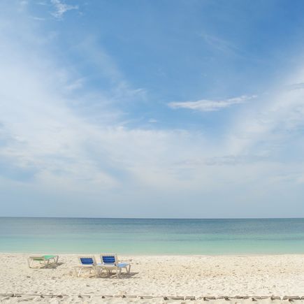 Ein Sandstrand mit flachem Wasser und einem blauen Himmel.