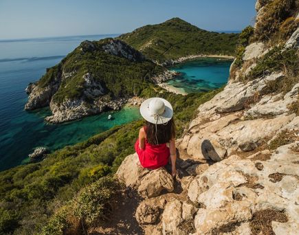 Eine Person blickt von einer Klippe auf eine Bucht.