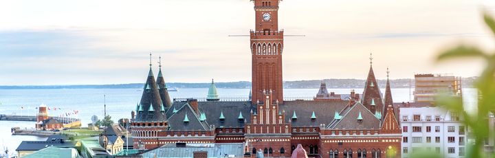 Blick auf die Stadt Helsingborg mit seinem Kirchturm und einigen Häusern. Im Hintergrund ist Wasser zu sehen.