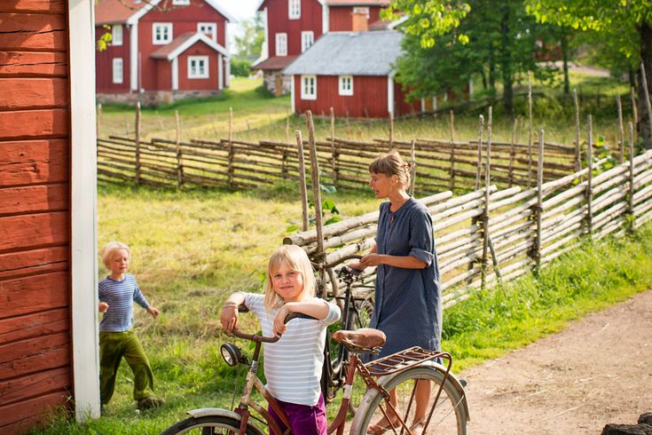 Ein traditionelles schwedisches Holzhaus mit einem roten Dach und einem Fahrrad davor. Die Szene ist ländlich und idyllisch.