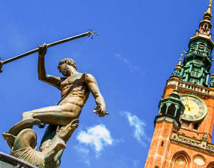 Eine Statue auf einem hohen Turm in einer Stadt.