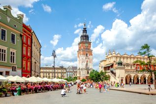 Marktplatz von Krakau, mittig im Hintergrund ist der Rathausturm zu sehen. Umgeben von vielen alten bunten Häusern.