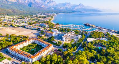 Blick über die Hotels, den vorangehenden Strand und das blaue Meer. Strahlend blauer Himmel und Berge im Hintergrund