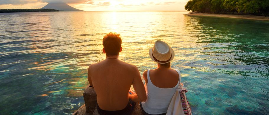 Ein Paar sitzt am Strand bei Sonnenuntergang.