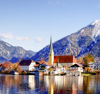 Eine Stadt am Ufer eines Sees, umgeben von schneebedeckten Bergen, Bayern. Tegernsee.