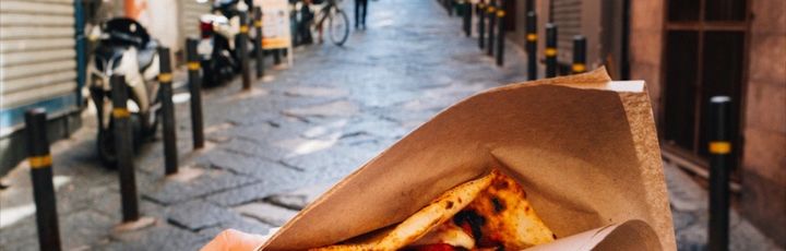 Eine Person hält ein Stück Pizza.