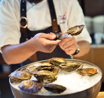 Person isst frische Austern und Meeresfrüchte an einem Tisch in einem schwedischen Restaurant.
