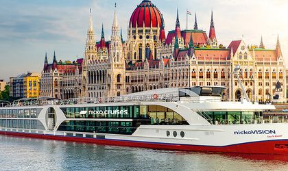 Ein Flusskreuzfahrtschiff auf der Donau in Budapest, mit dem Parlament im Hintergrund.