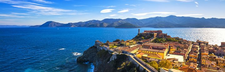 Panoramablick auf Portoferraio auf Elba mit der Festung, dem Hafen und dem klaren blauen Meer unter strahlendem Himmel.