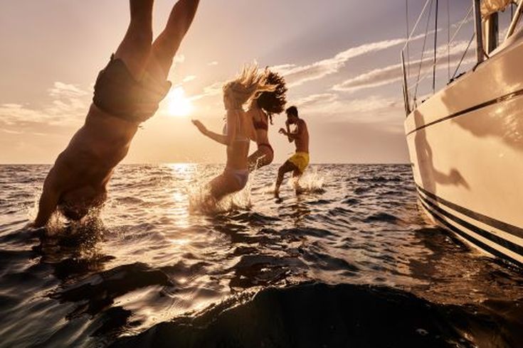 Eine Familie springt ins Wasser vom Boot aus.