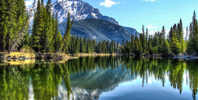 Der Bow Lake im Banff Nationalpark, Alberta, Kanada, spiegelt die majestätischen Rocky Mountains und den Bow River wider, umgeben von schneebedeckten Gipfeln und einem klaren, türkisfarbenen Wasser.