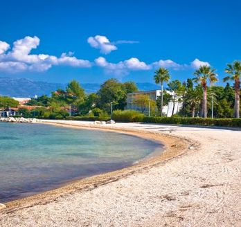 Ein Sandstrand mit Palmen und türkisblauem Wasser.