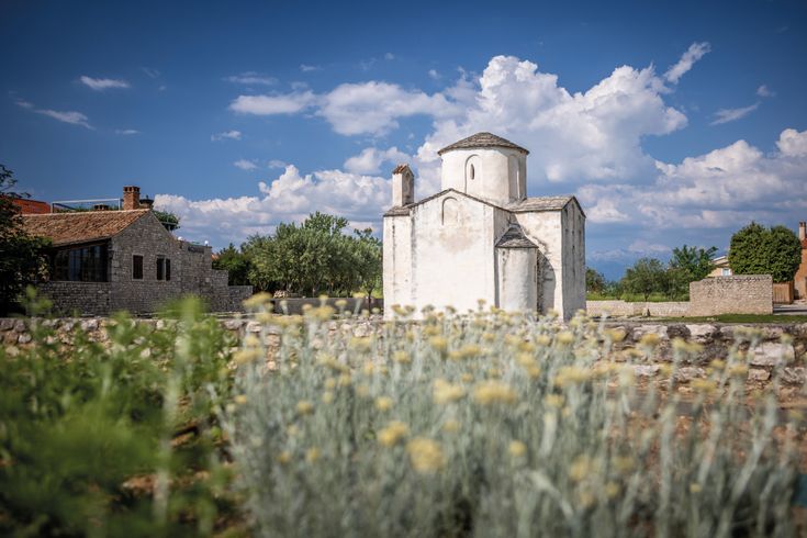 Eine historische Kirche in Nin, Kroatien, umgeben von trockener Vegetation.
