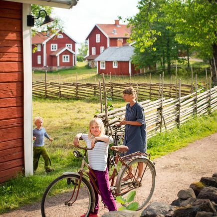 Ferienhaus Urlaub Schweden Kinder mit Fahrrad zwischen roten Häuschen