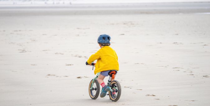 Kind auf Laufrad, Sandstrand in Hardelot, Frankreich