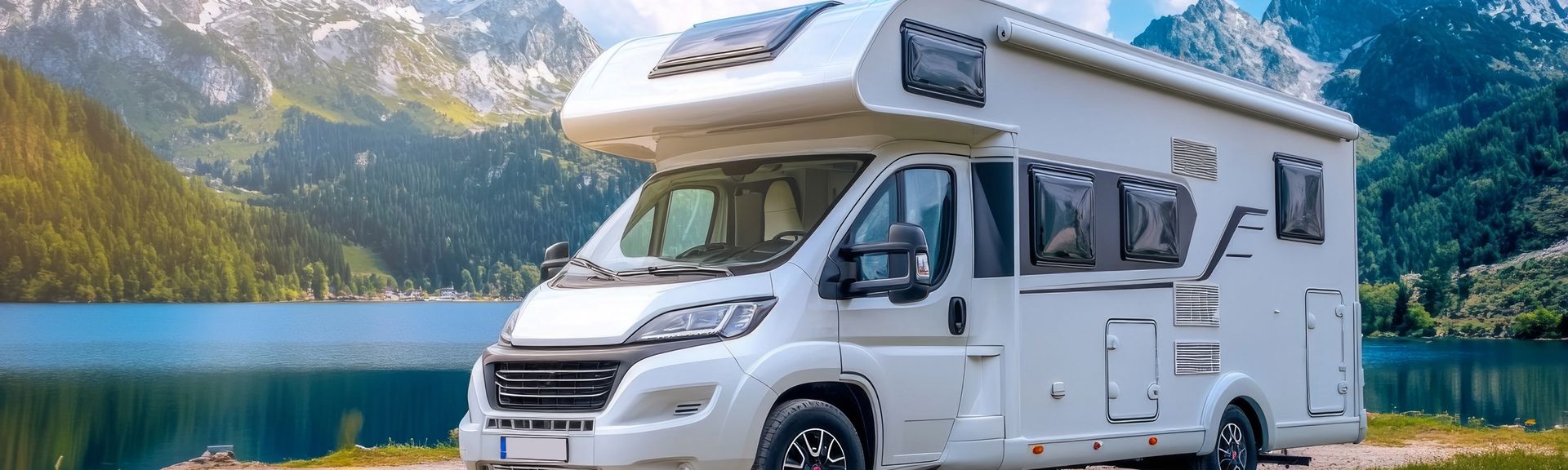 Ein modernes Weinsberg Carahome 650 MEG Wohnmobil steht auf einem Asphaltplatz vor einem grünen Wald unter einem wolkenverhangenen Himmel, bereit für die Reise.