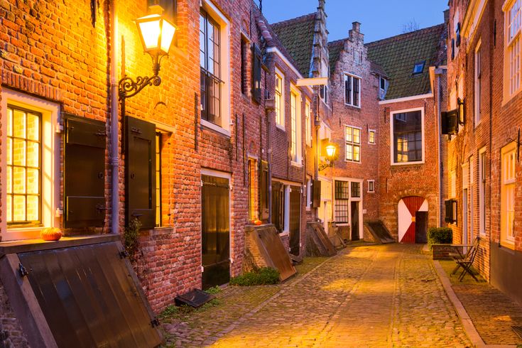 Eine enge Gasse in einer Stadt bei Nacht, mit beleuchteten Gebäuden.