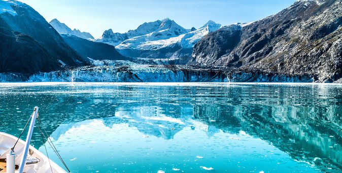 Ein Schiff fährt auf einem Gletschersee, umgeben von schneebedeckten Bergen.