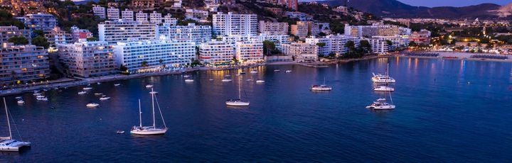 Blick auf den kleinen Hafen von Costa Calma. Einige Botte im Wasser, kleiner Strandabschnitt und dahinter Hotels und Gebäude.