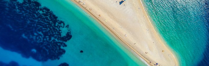 Ein Sandstrand mit türkisfarbenem Wasser.