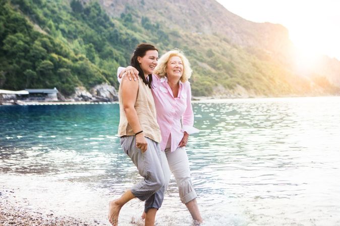 2 Frauen am Srand. Meer und Berge im Hintergrund