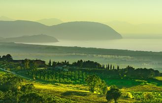 Eine weite Landschaft mit grünen Hügeln und dem Meer.