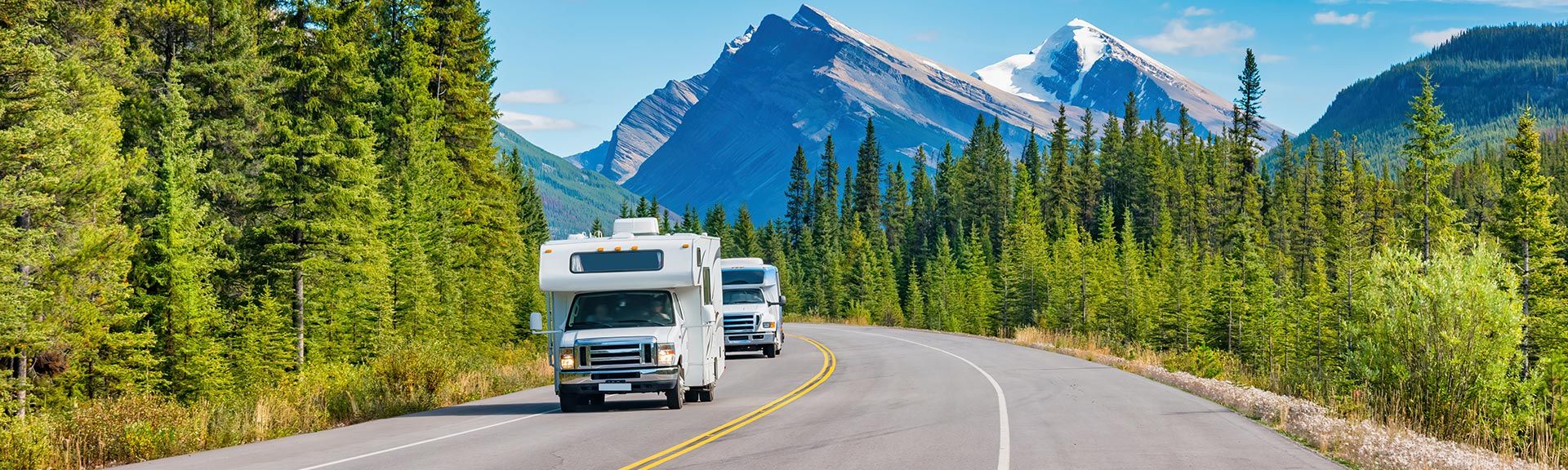 Zwei Camper auf der Straße vor einer Berglandschaft