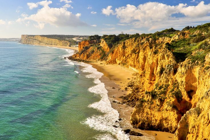 Eine felsige Küstenlinie mit türkisfarbenem Wasser und einem Strand.