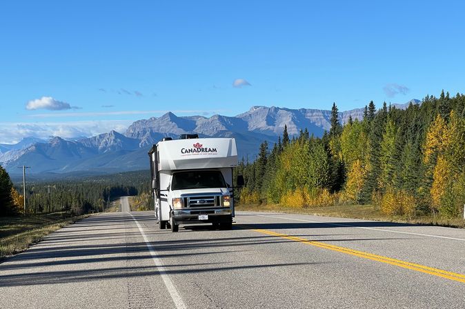 Camper fährt auf langer Straße mit Bergen in Kanada