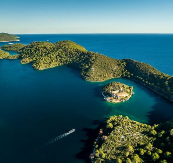 Eine Luftaufnahme einer bewaldeten Küstenlinie mit vielen Buchten und türkisfarbenem Wasser.
