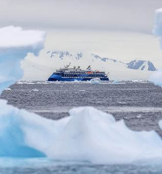 Eine eisige Landschaft mit schwimmenden Eisbergen und einem Schiff in der Ferne.