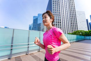 Joggende Frau im pinken Shirt läuft durch Tokyo