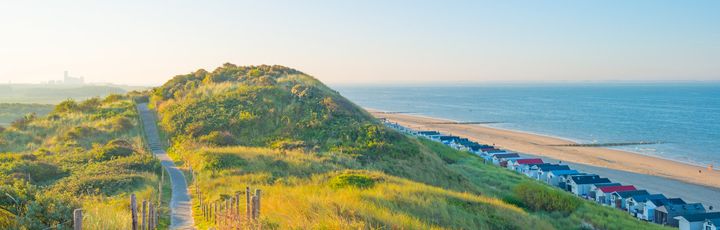 Eine hügelige Landschaft mit Gras und einem Fluss oder Meer.