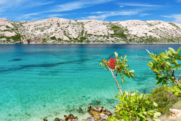 Eine Luftaufnahme einer Insel mit einem Strand und türkisfarbenem Wasser.