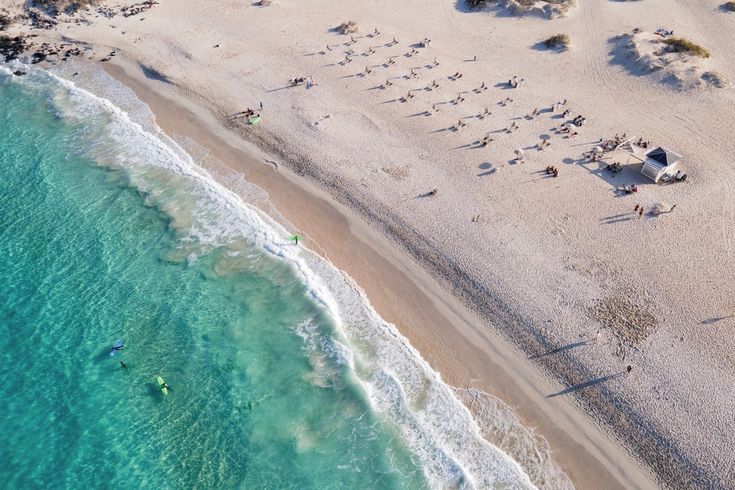 Ein Sandstrand mit Dünen und blauem Meer.