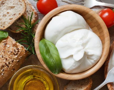 Burrata, Tomaten, Basilikum auf einem kleinen Teller angerichtet.