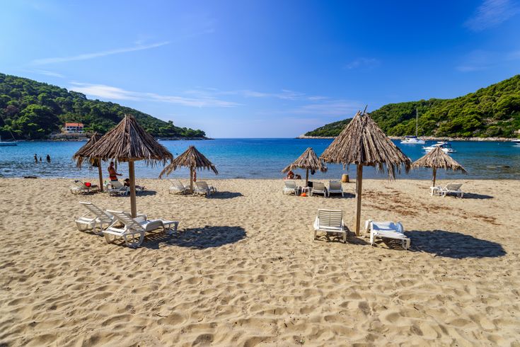 Ein Sandstrand mit Sonnenschirmen und Liegestühlen.