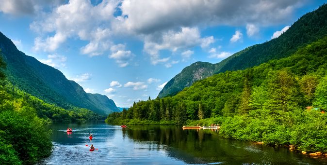 Eine malerische Flusslandschaft im Jacques-Cartier-Nationalpark in Quebec, Kanada, mit dem Jacques-Cartier River, der sich durch ein bewaldetes Tal schlängelt, umgeben von Herbstfarben.