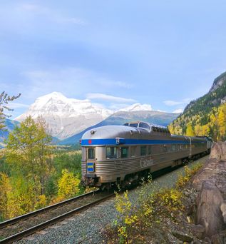 Zug fährt durch eine bergige Landschaft mit grüner Natur