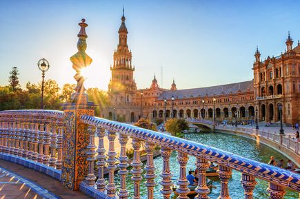 Plaza de España in Sevilla, Spanien, bei Sonnenuntergang, mit einem Kanal und einer verzierten Brücke im Vordergrund