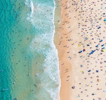 Strand mit vielen Strandbesuchern und hellblauem Meer in Australien 