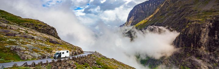 Grünes Tal mit Fluss und sprudelnden Wasserfällen in Norwegen, umgeben von hohen Bergen.