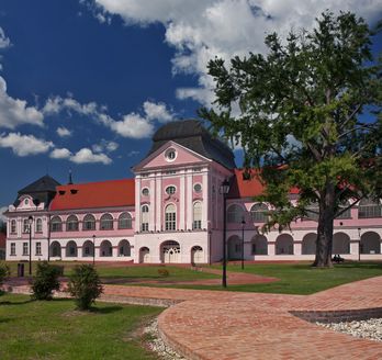 Ein Schloss mit einem roten Dach in einer grünen Landschaft.