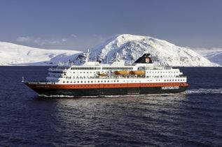 Kreuzfahrtschiff fährt mit Eisbergen im Hintergrund