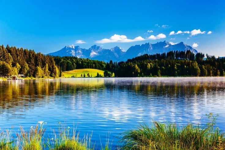 Ein See mit blauem Wasser, umgeben von grünen Bergen.