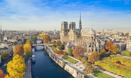 Eine Luftaufnahme von Paris mit dem Eiffelturm, der Seine und Gebäuden. Die Stadt erstreckt sich weitläufig und zeigt ihre ikonischen Wahrzeichen.