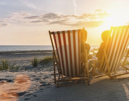 Paar sitzend in Sonnenstühlen am Strand