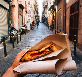 Eine Person hält ein Stück Pizza.