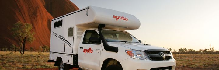Abenteuerliches Apollo-Wohnmobil vor dem majestätischen Uluru in Australiens Outback bei goldener Abendstimmung